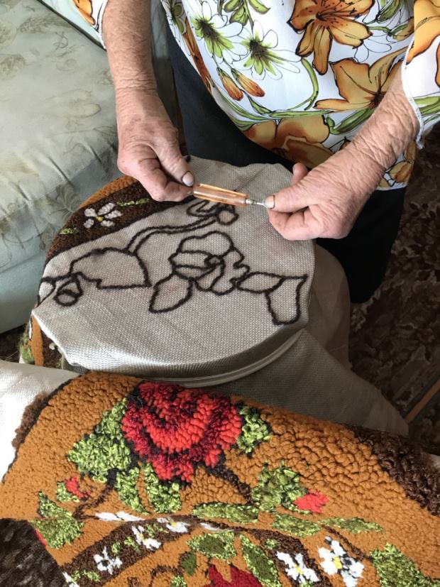 Руки бабушки за вышиванием ковра